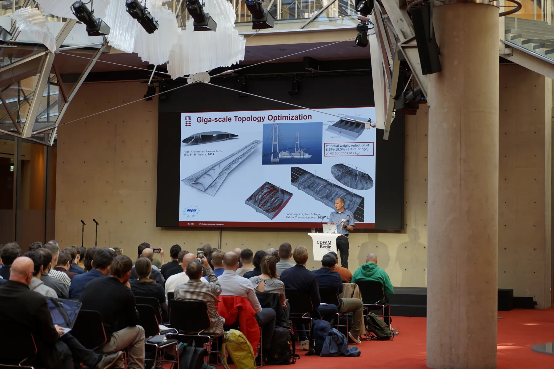 An audience in a hall at FormNext watching a talk on topology optimisation.