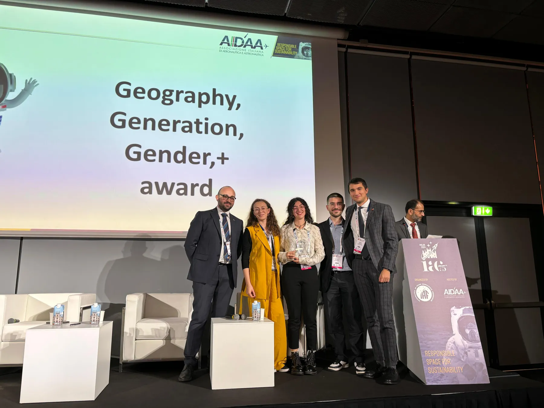 Team members on stage at IAC 2024 under a screen reading Geography, Generation, Gender award.