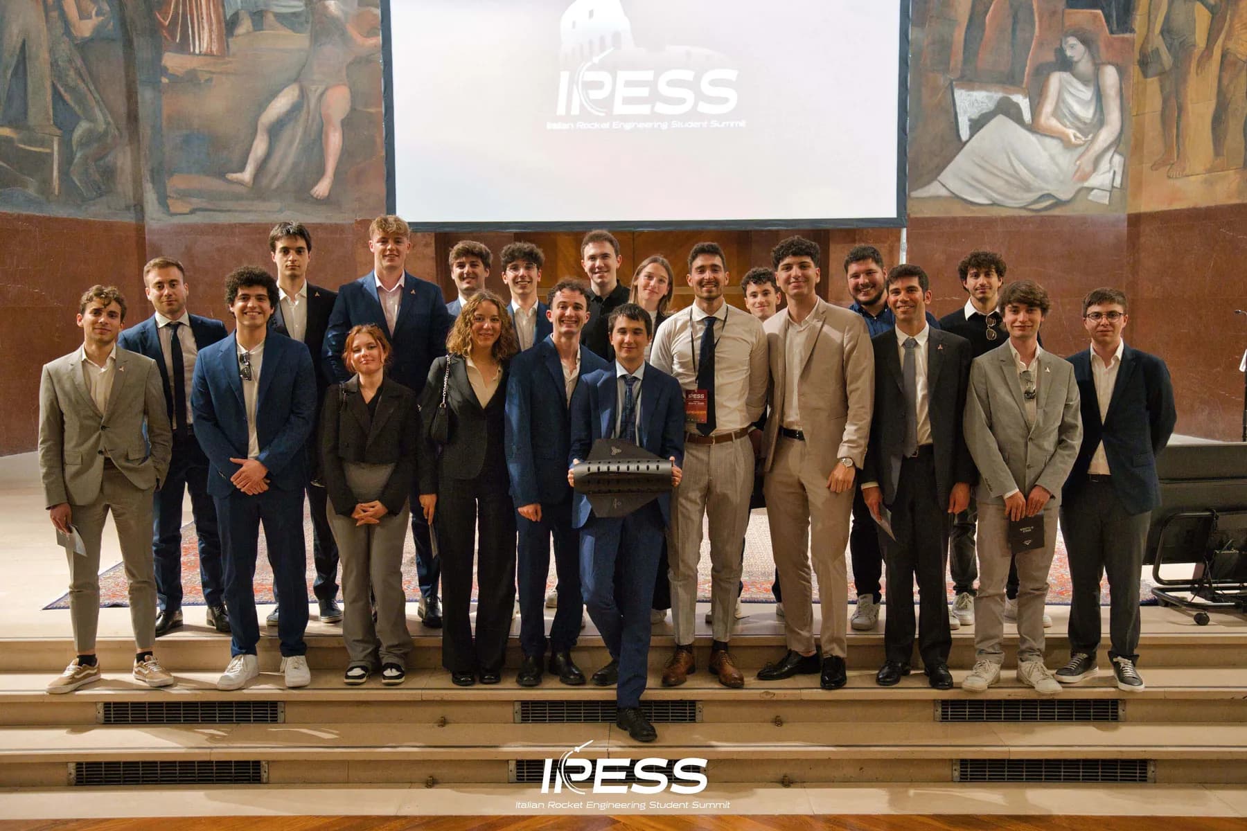 Students from Italy's rocket teams on stage under a fresco at IRESS 2025 in Rome.