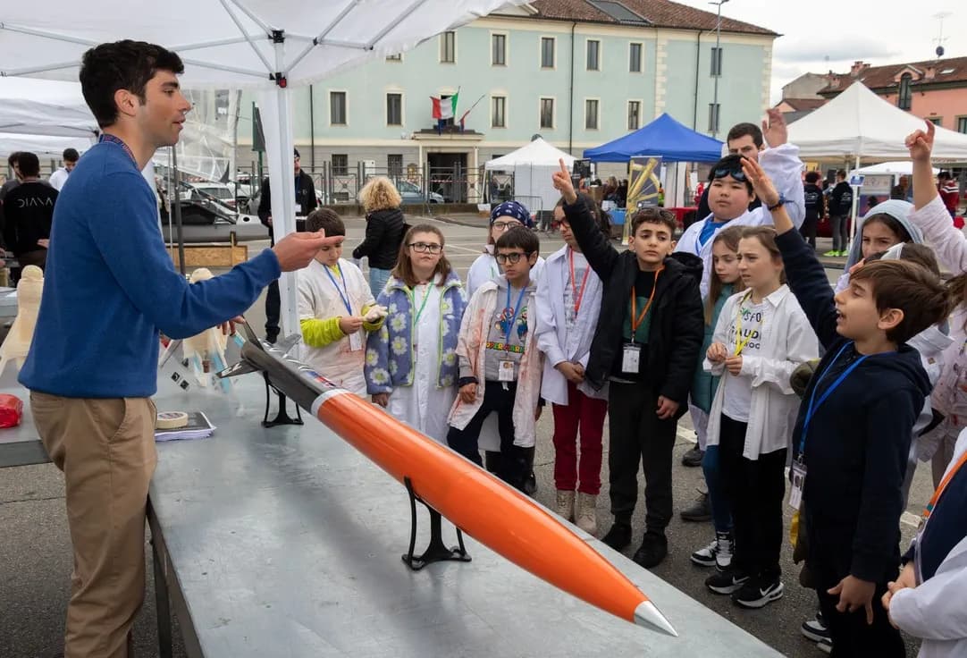 Children in a square gathered round a team member and the newly painted Cavour.