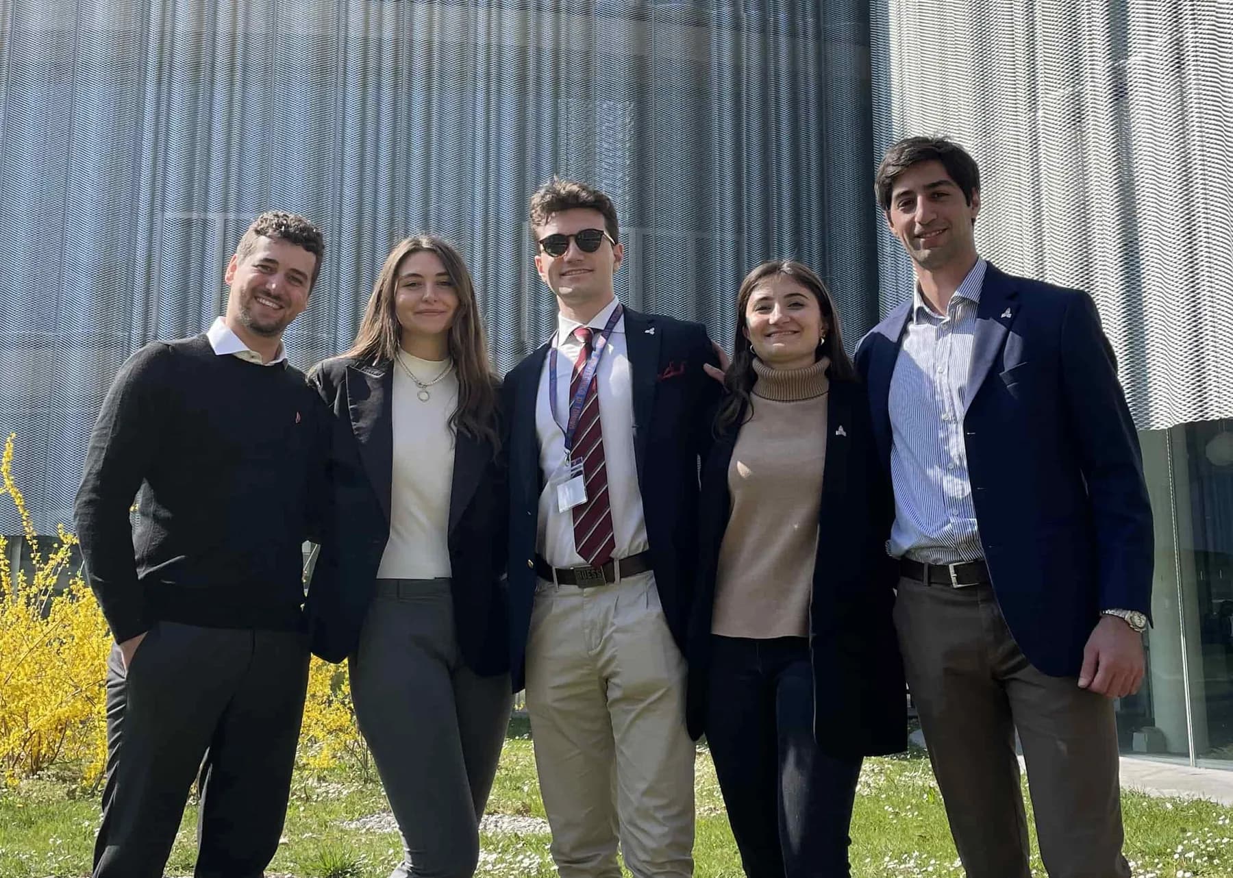 Five team members in front of a building at Bocconi University.